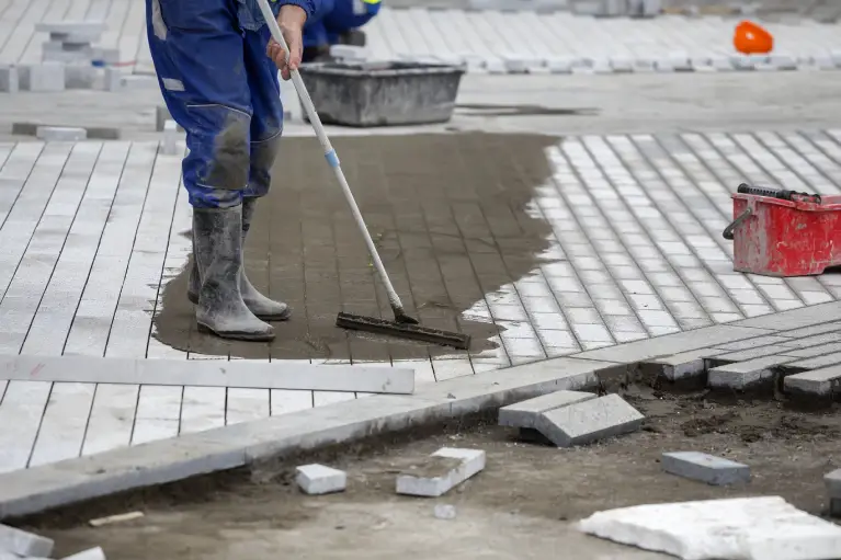 Contractor installing traditional brick pavers in a herringbone walkway pattern in Fullerton, California