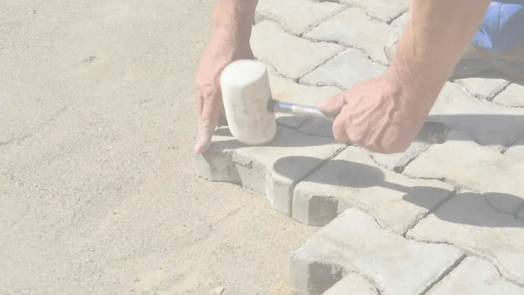 Close-up of contractor laying pavers with a rubber mallet on sand base for a Southern California home project