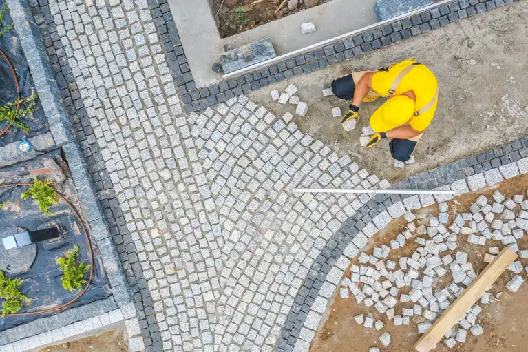 Contractor installing curved patio pavers to create a private backyard retreat in Southern California