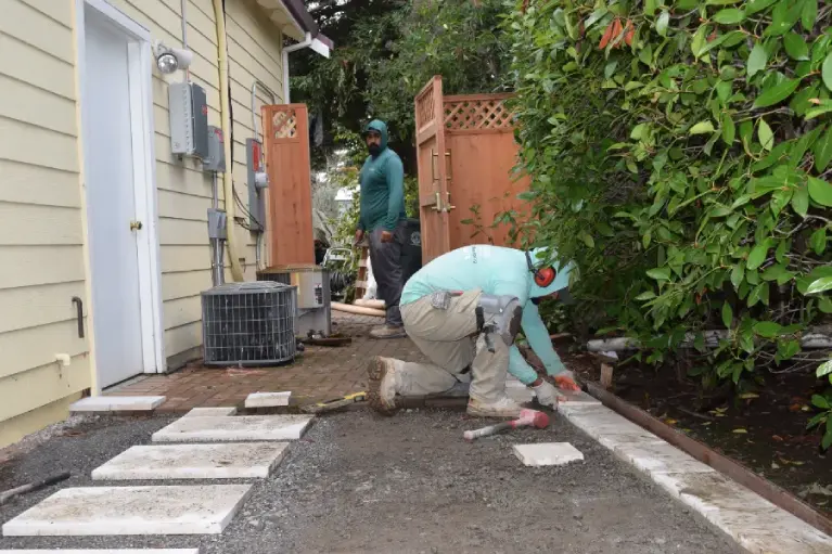 Paving contractors installing stone walkway beside a home in Orange County, California showcasing expert craftsmanship