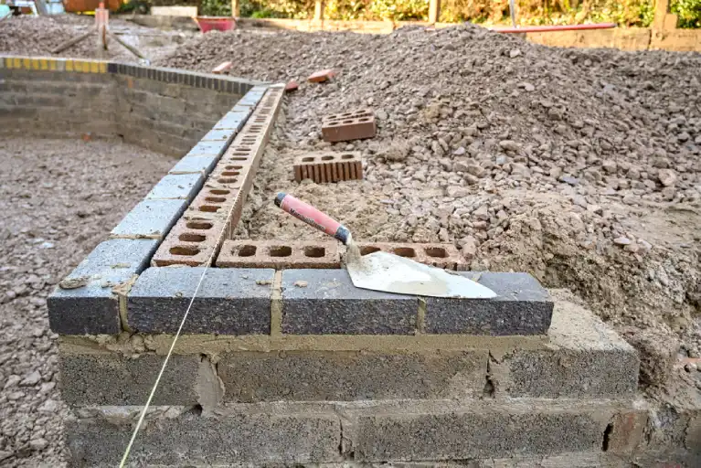Brick retaining wall under construction in Irvine showing foundation structure and mortar work to prevent soil erosion and support sloped terrain