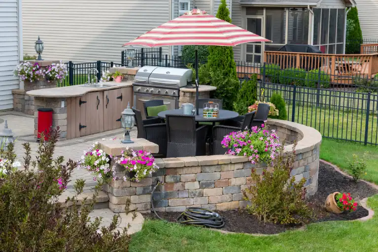 Curved retaining wall integrated into a landscaped outdoor kitchen and patio area in Irvine, enhancing garden aesthetics and space functionality