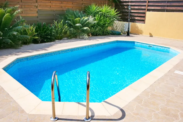 Private swimming pool in Morello Valley, California with a light-colored slip-resistant paver deck and tropical landscaping