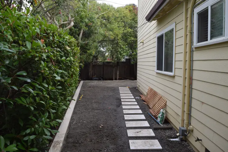 Before image showing groundwork preparation with decorative pavers being set in place beside a Southern California home, prior to concrete walkway and turf installation.
