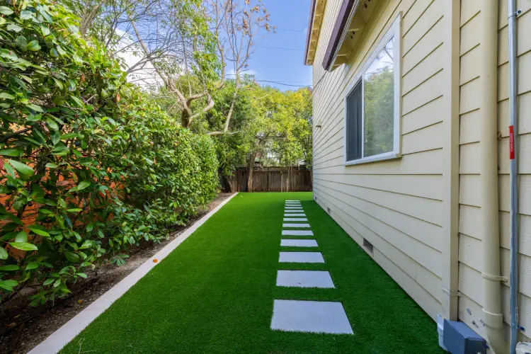 After image of durable concrete walkway with decorative square pavers set in artificial turf beside a freshly painted Southern California home.