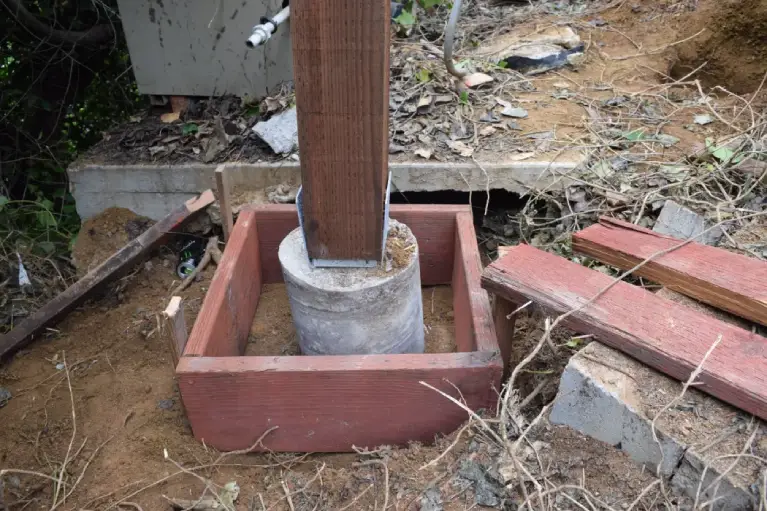 Close-up of expert deck foundation repair showing post secured in a concrete footing—essential support for building a safe and long-lasting deck structure.