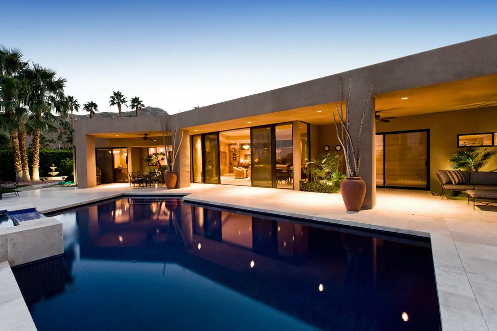 Luxury Southern California backyard with a modern pool and patio, featuring warm lighting and seamless indoor-outdoor living