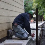 Worker building a retaining wall along the side of a Southern California home as part of a hardscape renovation project.