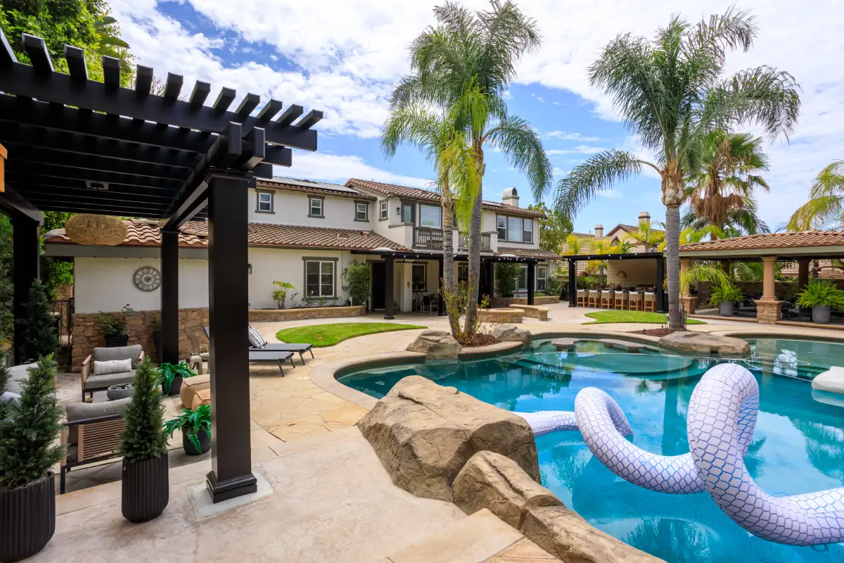 Black lattice pergola with 8x8 posts beside a pool, with patio covers across the Yorba Linda backyard