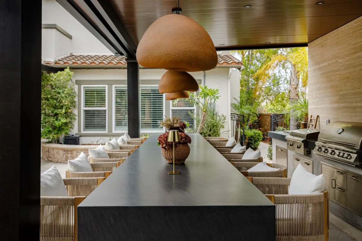 Long black granite bar under pendant lights and an insulated patio cover in a Yorba Linda outdoor kitchen